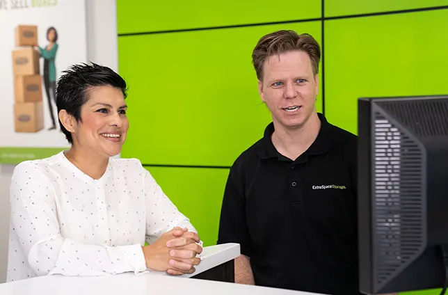 Man and woman smiling at computer in office setting