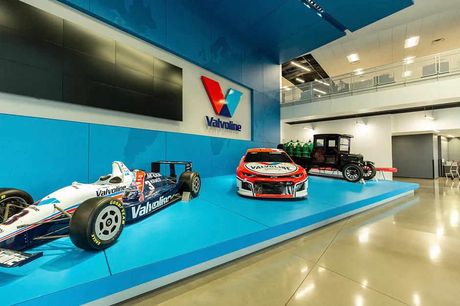 A bright display in the **Valvoline headquarters** featuring race cars and an antique vehicle.