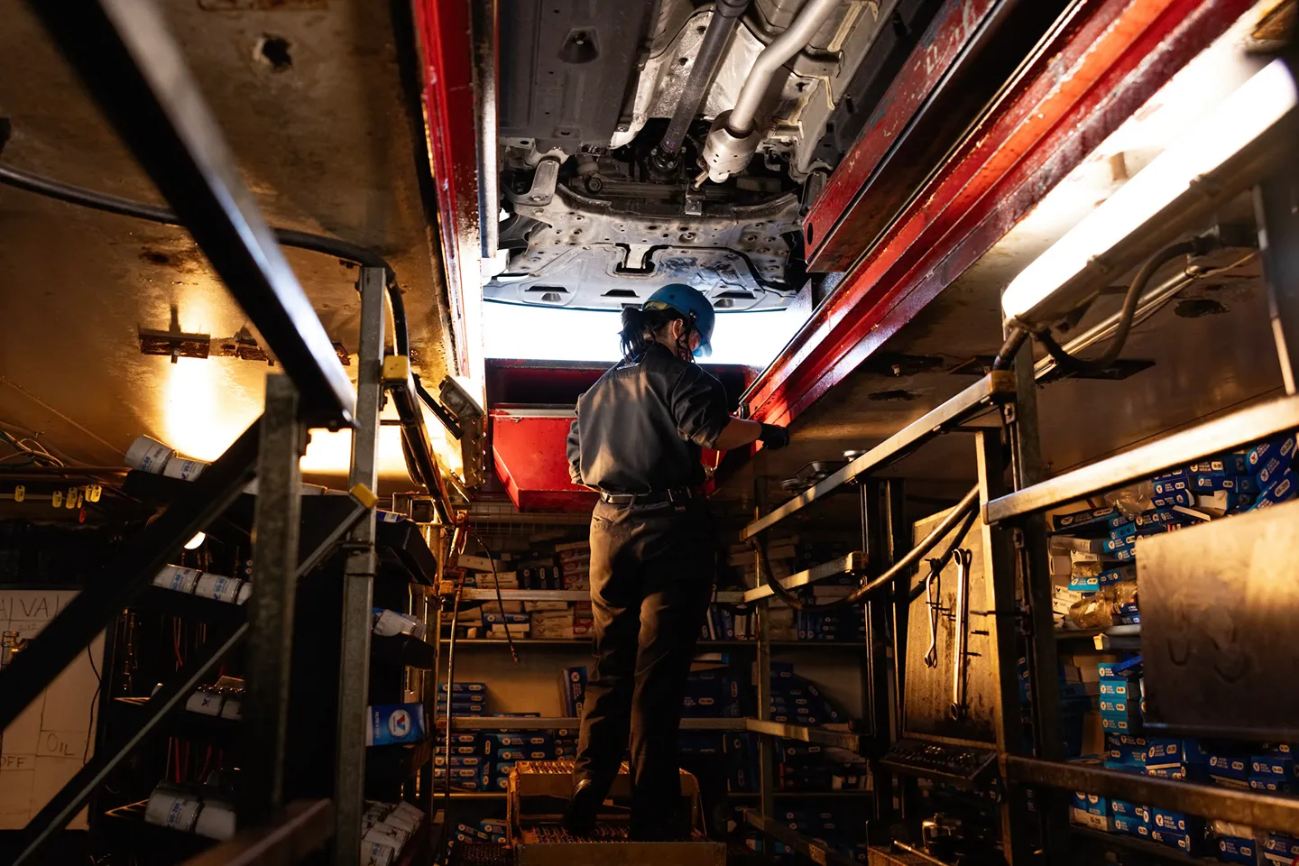A **Valvoline technician** is working on a car from beneath in the oil change pit.