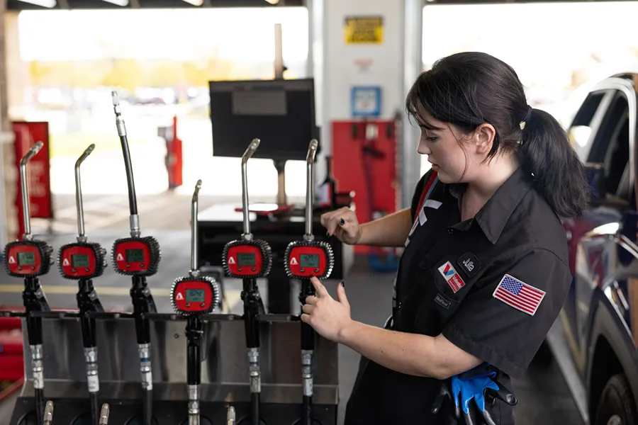A focused Valvoline female technician is adjusting the settings on oil dispensing gauges.