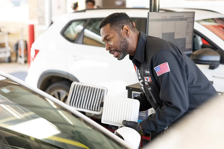 A **Valvoline technician** is showing a customer the difference between a clean and a dirty air filter.