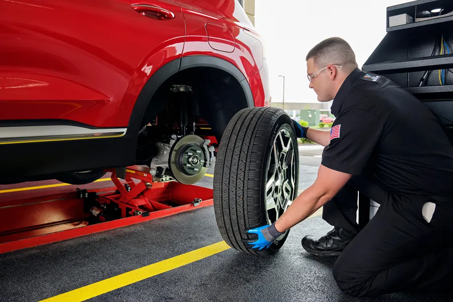 A **Valvoline technician** is inspecting a tire and wheel while performing a service.