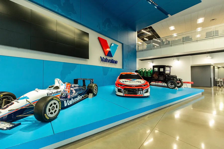 A bright display in the Valvoline headquarters featuring race cars and an antique vehicle.