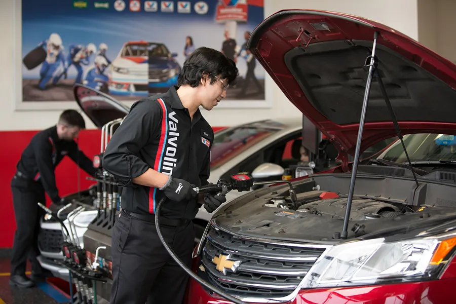 Two Valvoline technicians are performing vehicle services in a clean service bay.