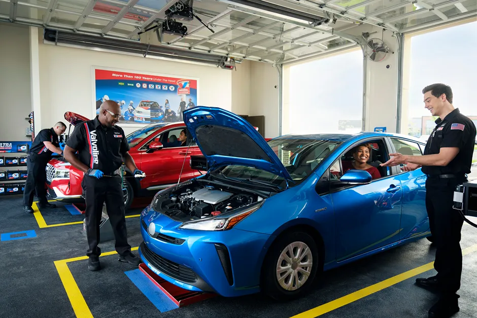 A busy **Valvoline service bay** with technicians servicing cars and smiling at customers.