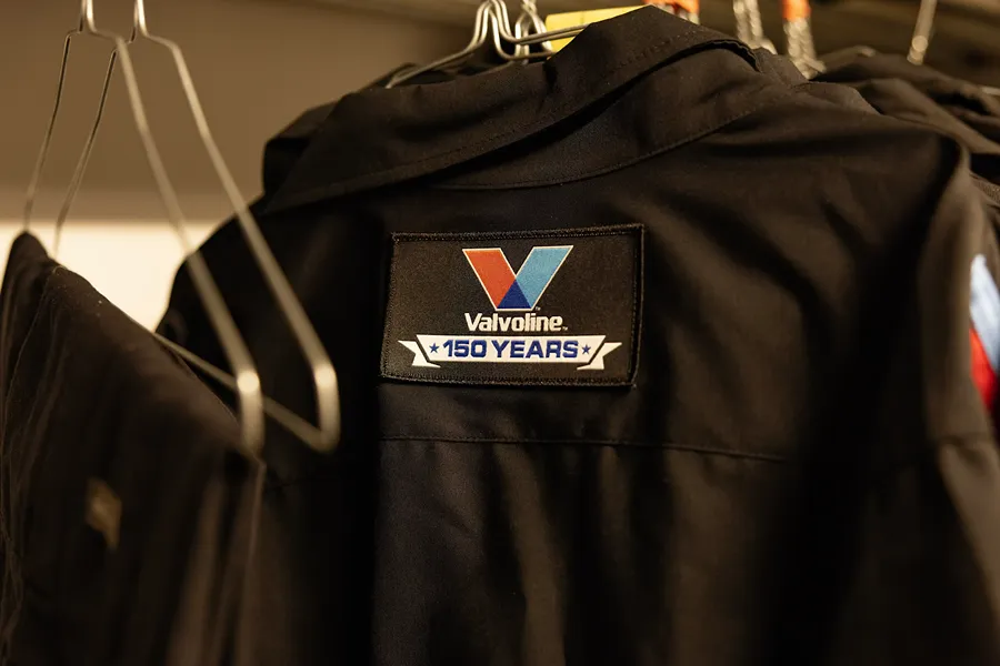 A close-up of a Valvoline 150 Years patch on a technician's uniform hanging on a rack
