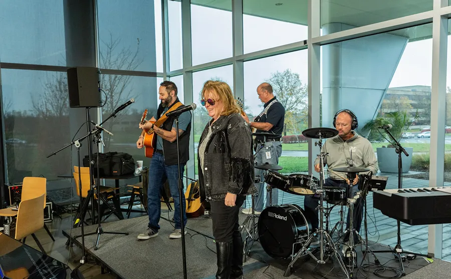A group of employees is performing live music together in a well-lit office space