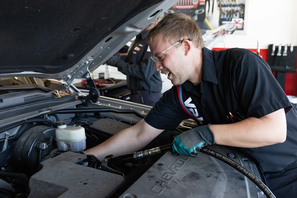 A focused Valvoline technician is performing an engine service on a customer's vehicle.
