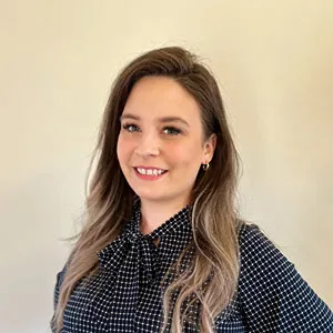 Woman with long hair smiling in polka dot shirt