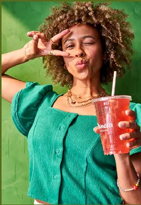 Woman in green top making silly face holding red drink with straw