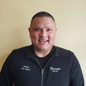 Man in Panera Bread jacket smiling with "Pedro 24 Years" on sleeve