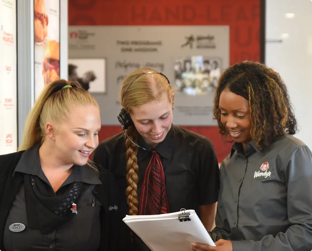 Three Wendy's employees review paperwork together
