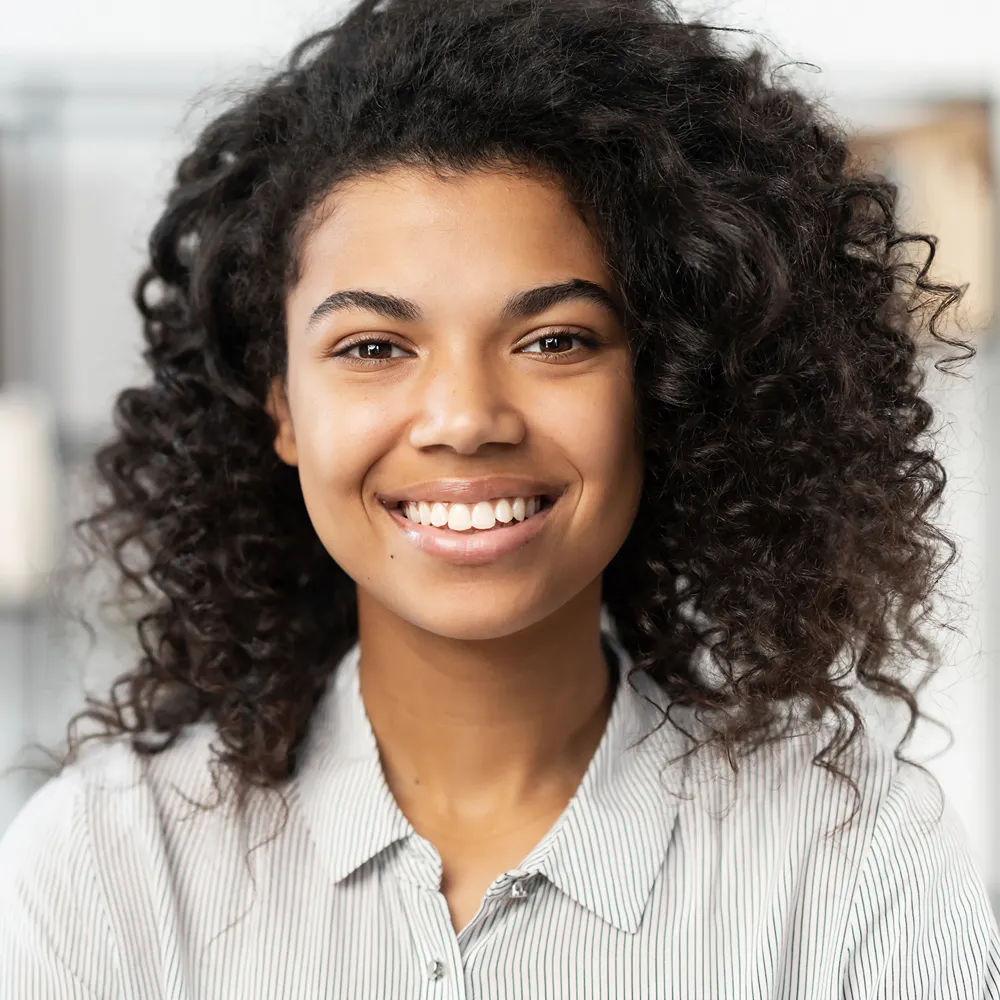 Smiling woman with curly hair wearing a collared shirt
