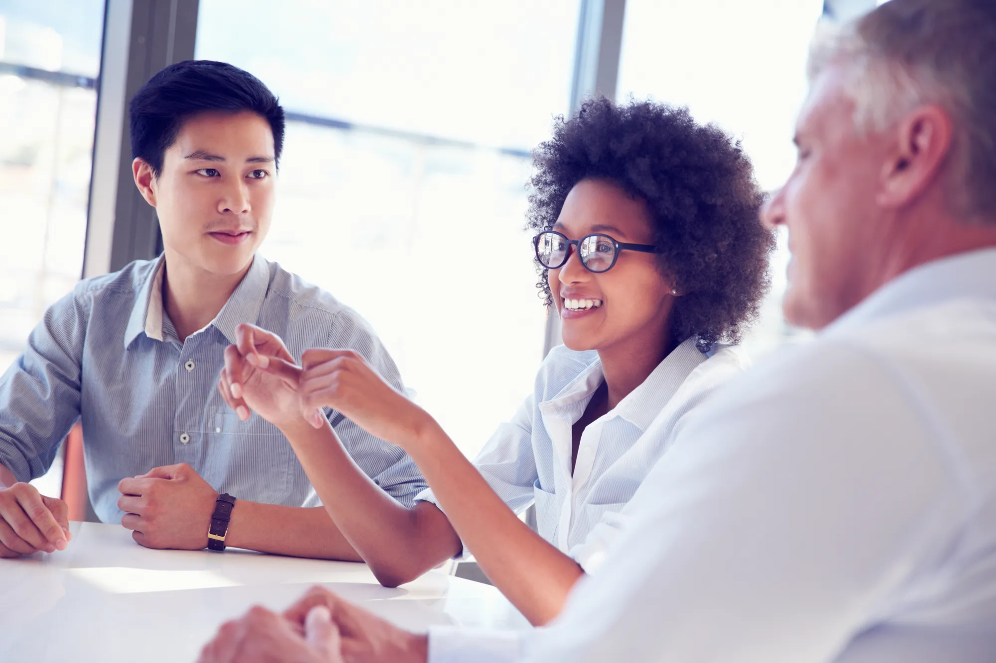 Three colleagues collaborating around a table during a meeting
