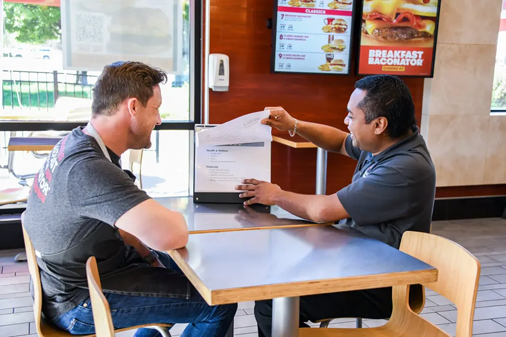 Two men smiling and reviewing a document together at a table