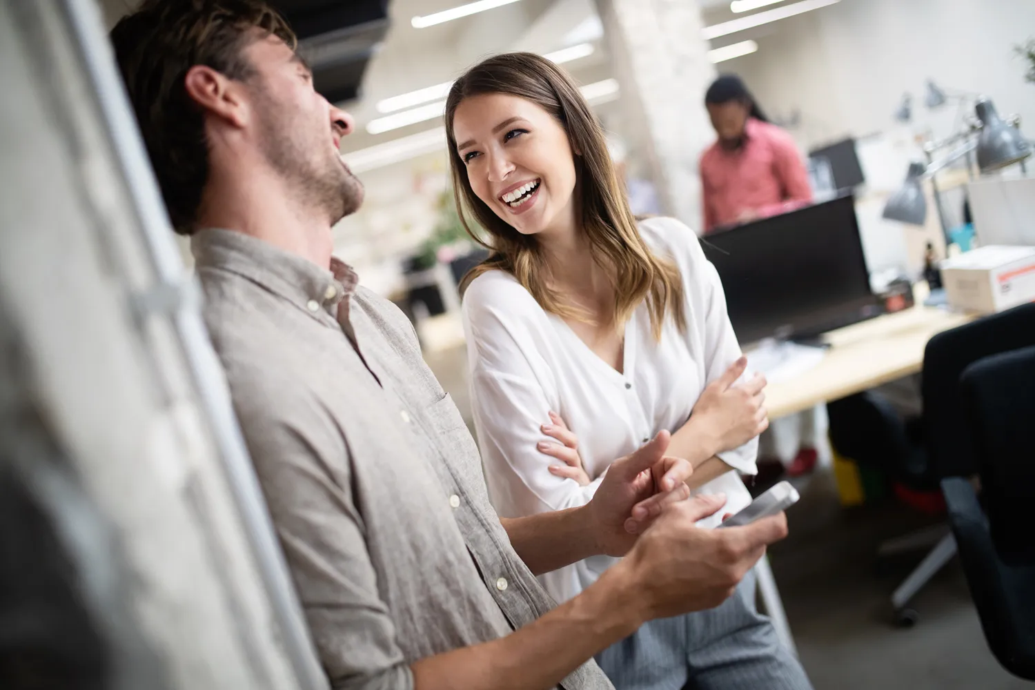 Two colleagues smiling and collaborating in a modern office setting