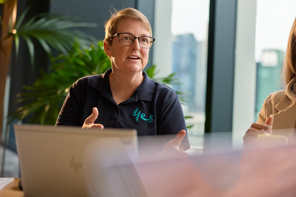 Two people working on a computer in a modern office with 'Optus 5G' screens