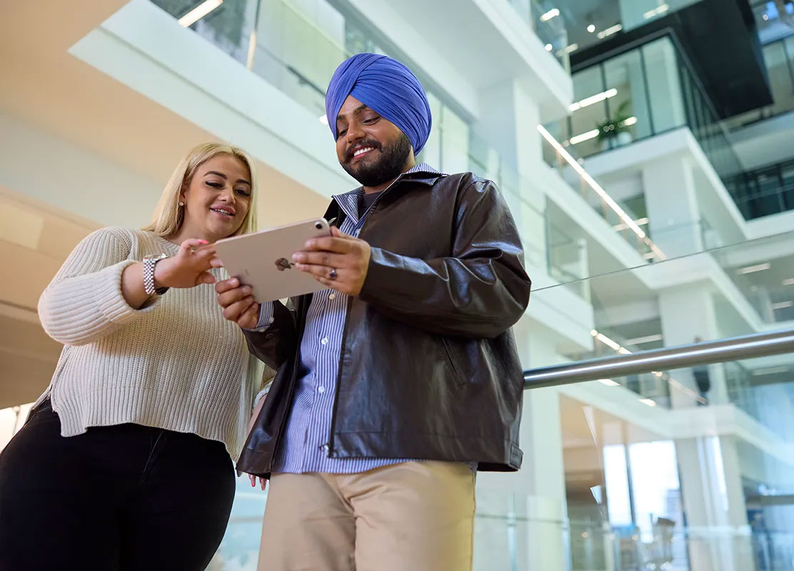 Two people working on a computer in a modern office with 'Optus 5G' screens