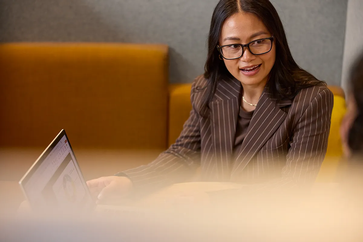 Two people working on a computer in a modern office with 'Optus 5G' screens