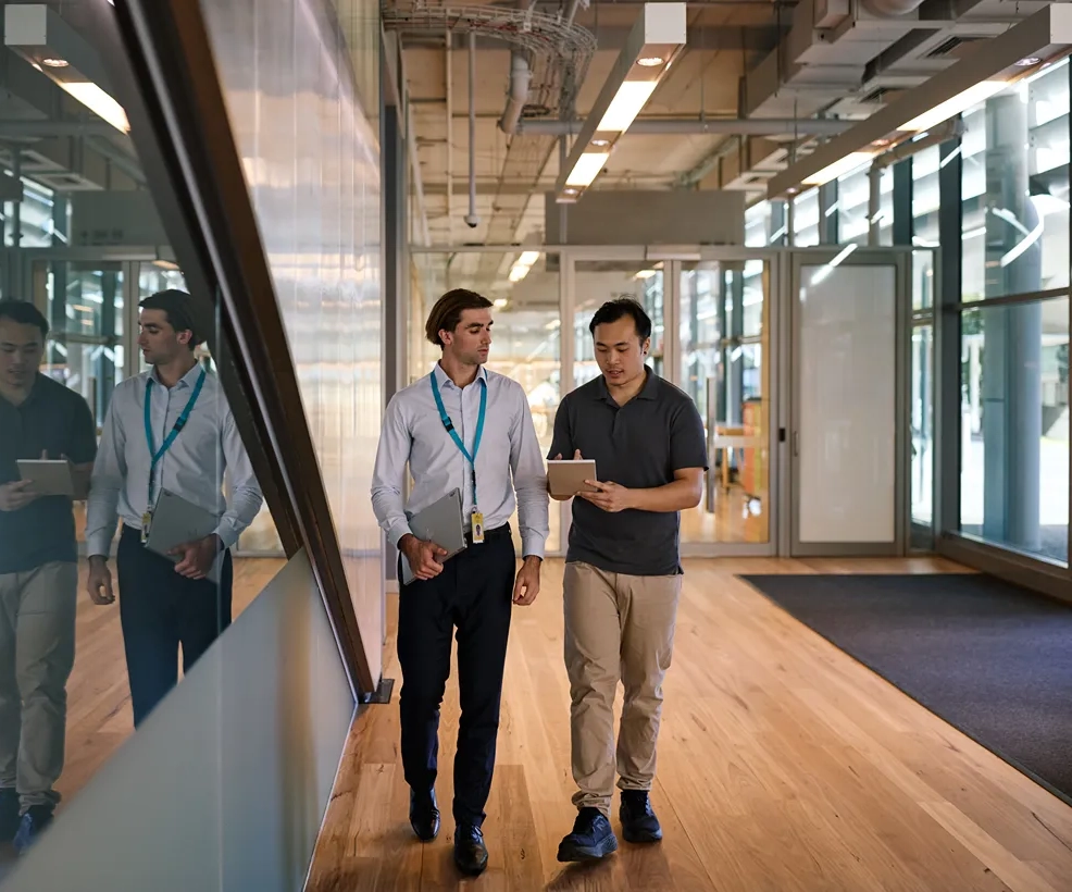 Man with tablet viewing data on a large screen in a dark room