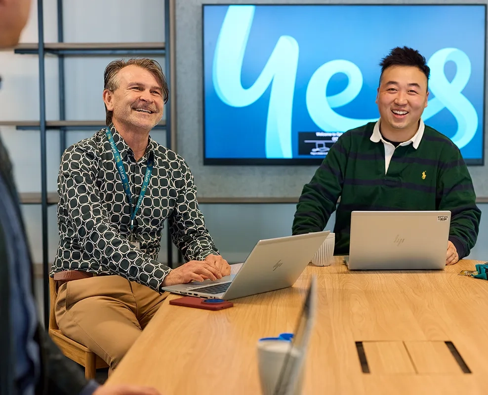 Two people talking at an outdoor cafe table with an umbrella