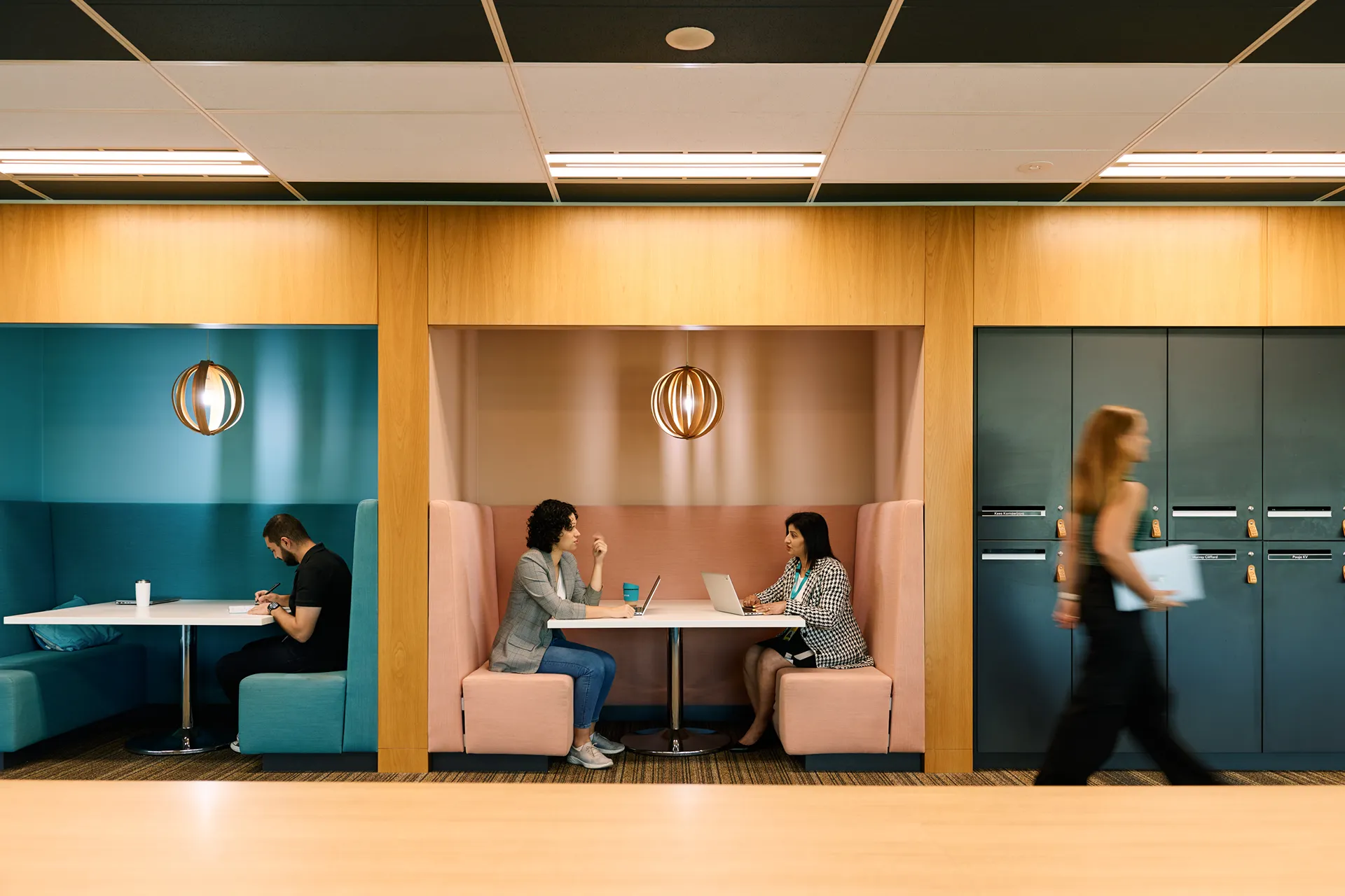 People working and talking in a modern office with colorful booths