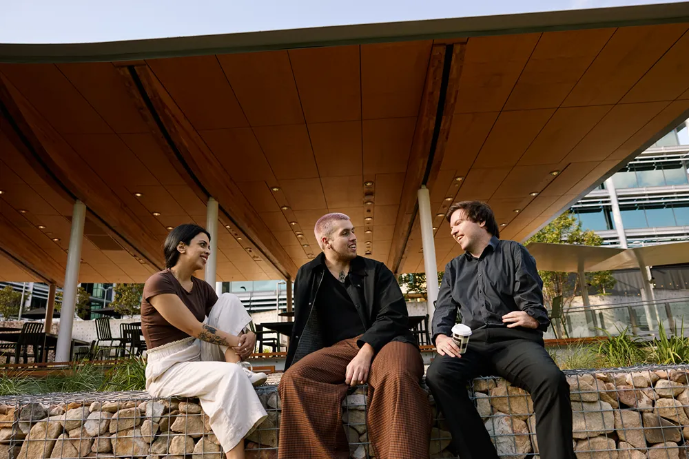Three diverse people chatting outdoors under a modern canopy