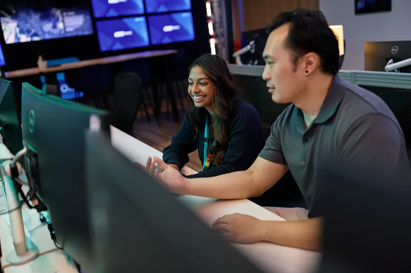 Two colleagues collaborating and smiling at a computer workstation