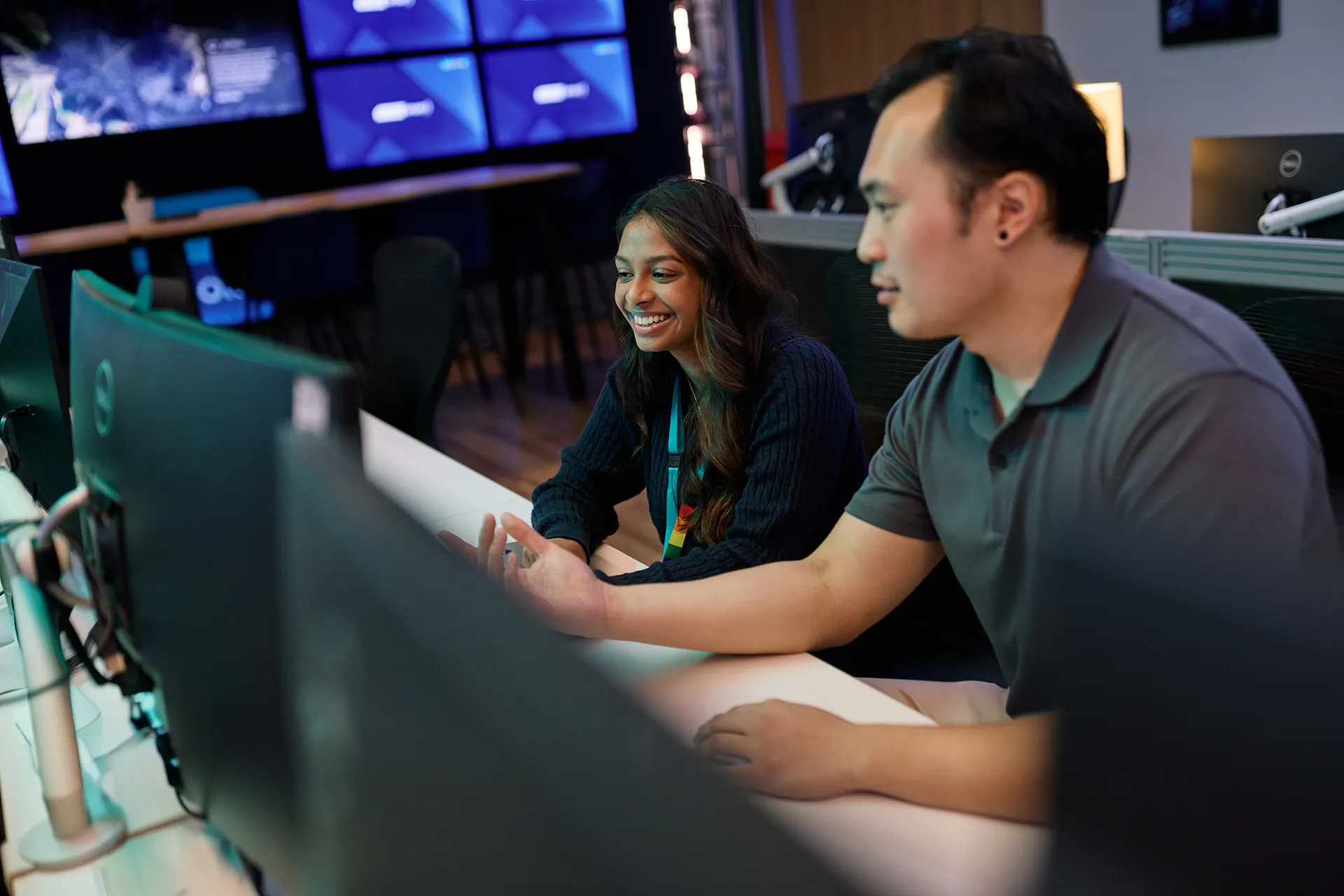 Two colleagues collaborating and smiling at a computer workstation