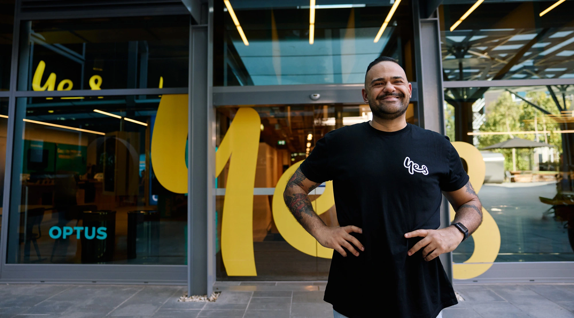 Man smiling in front of an Optus building