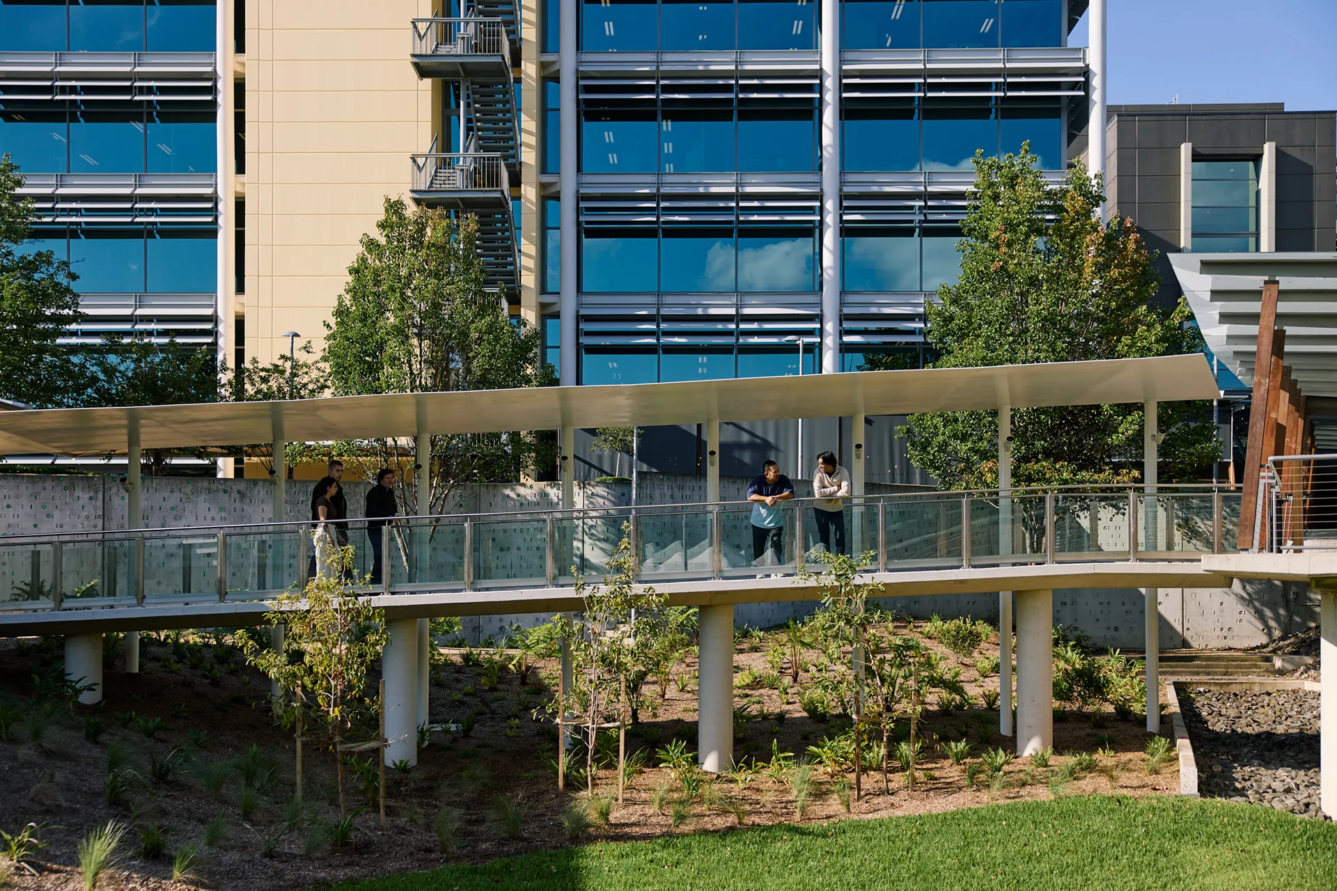 People walking on an elevated walkway connecting modern buildings