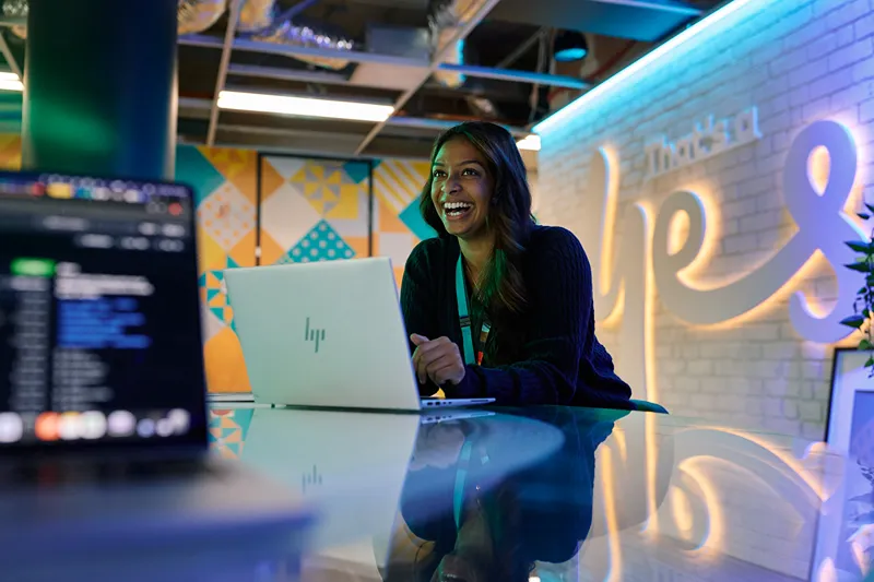 Smiling woman working on a laptop in a vibrant office