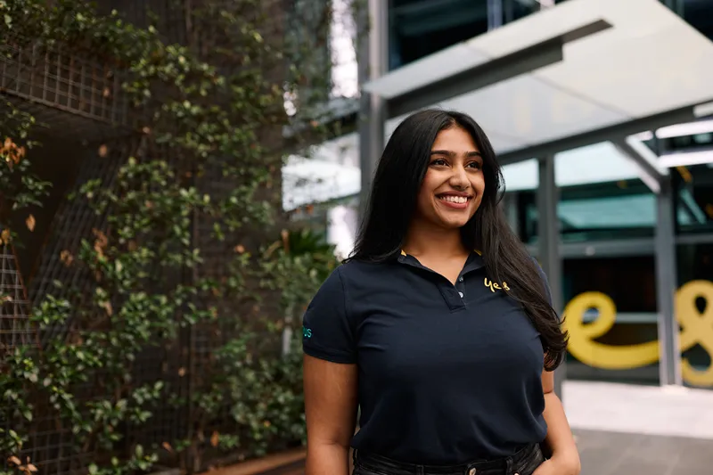 Smiling woman in a 'Yes' polo shirt standing outdoors