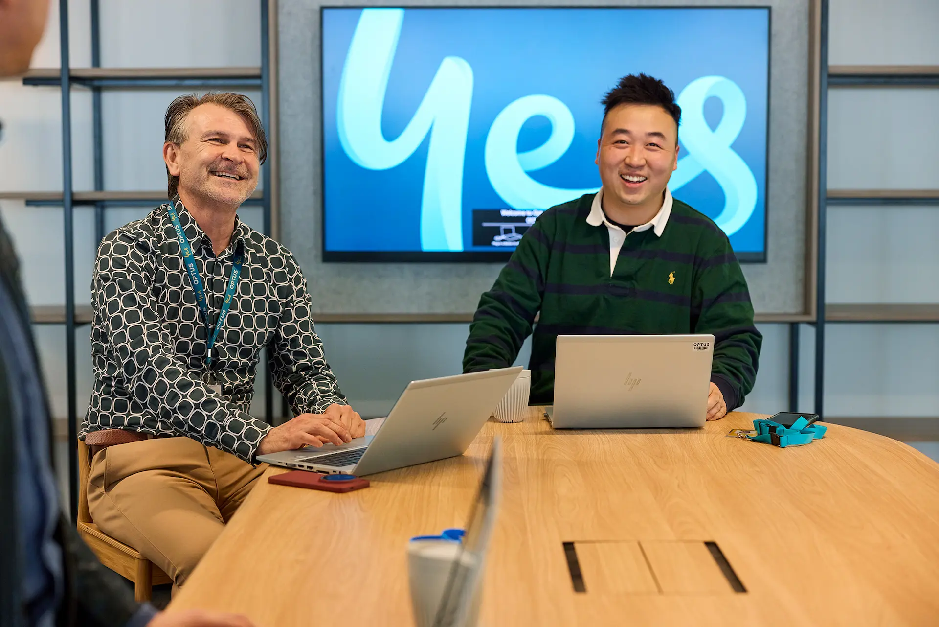 Two people talking at an outdoor cafe table with an umbrella