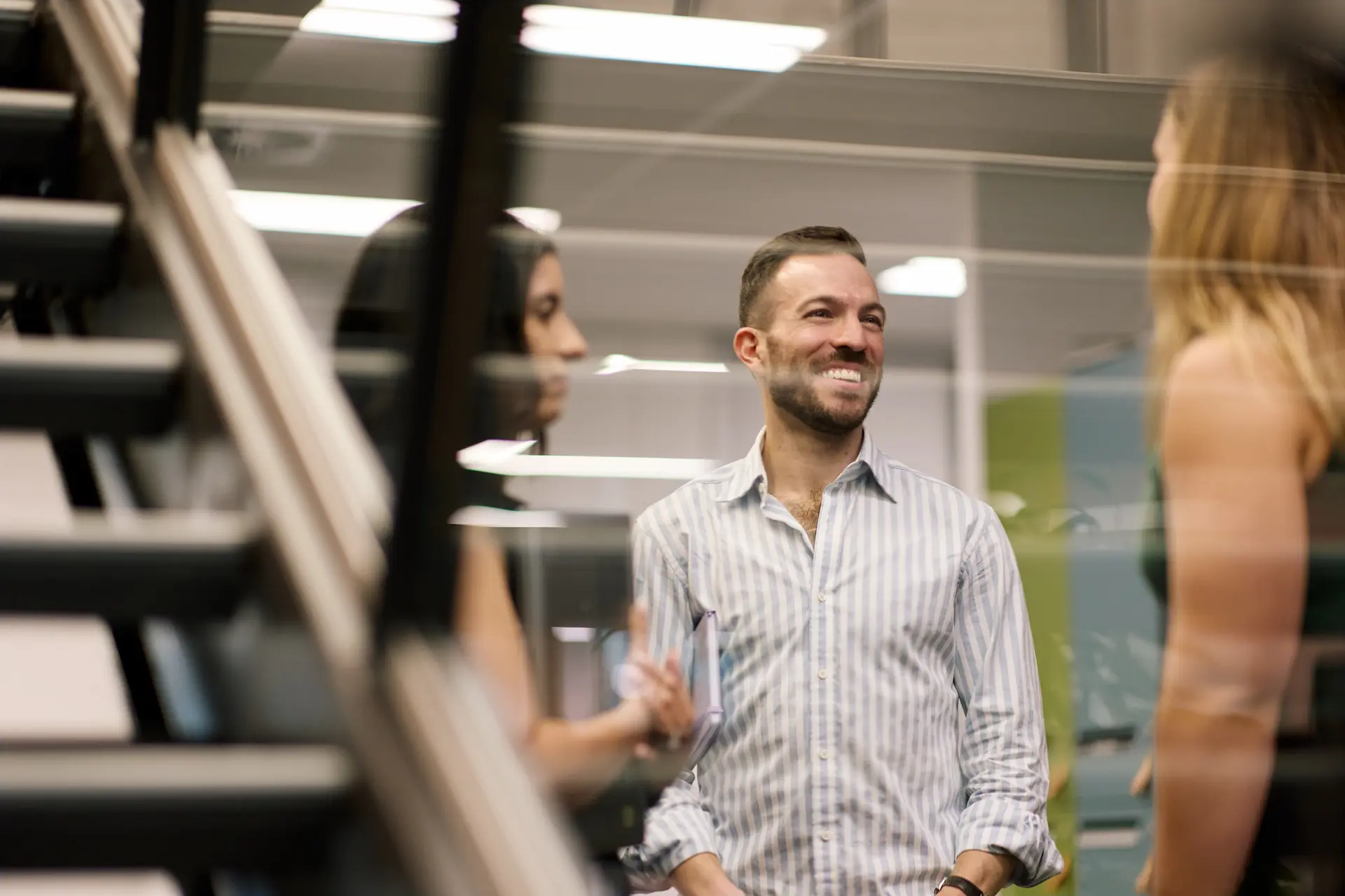 A group of people in a modern office setting gathered together smiling