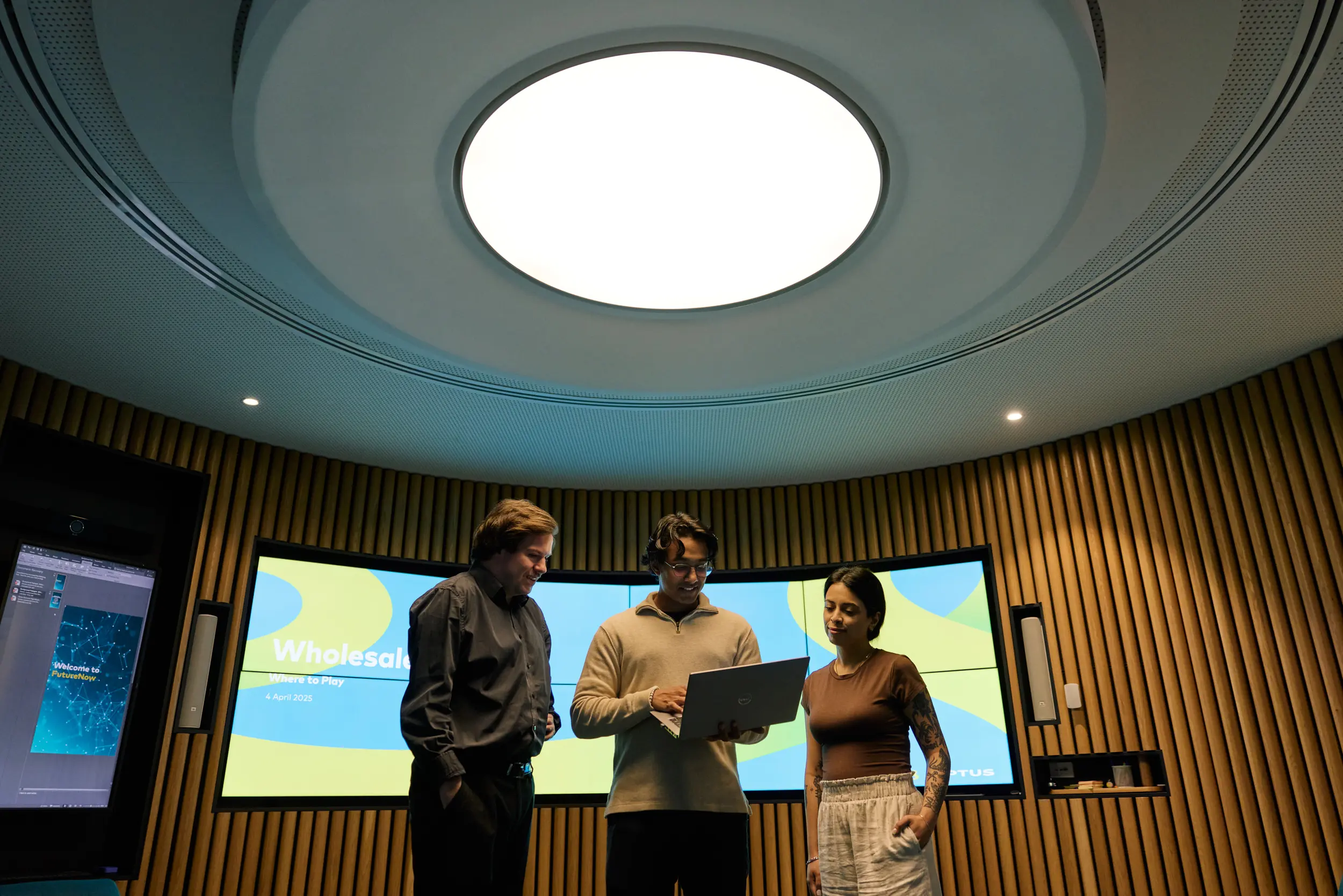 Three people huddled together looking at a laptop