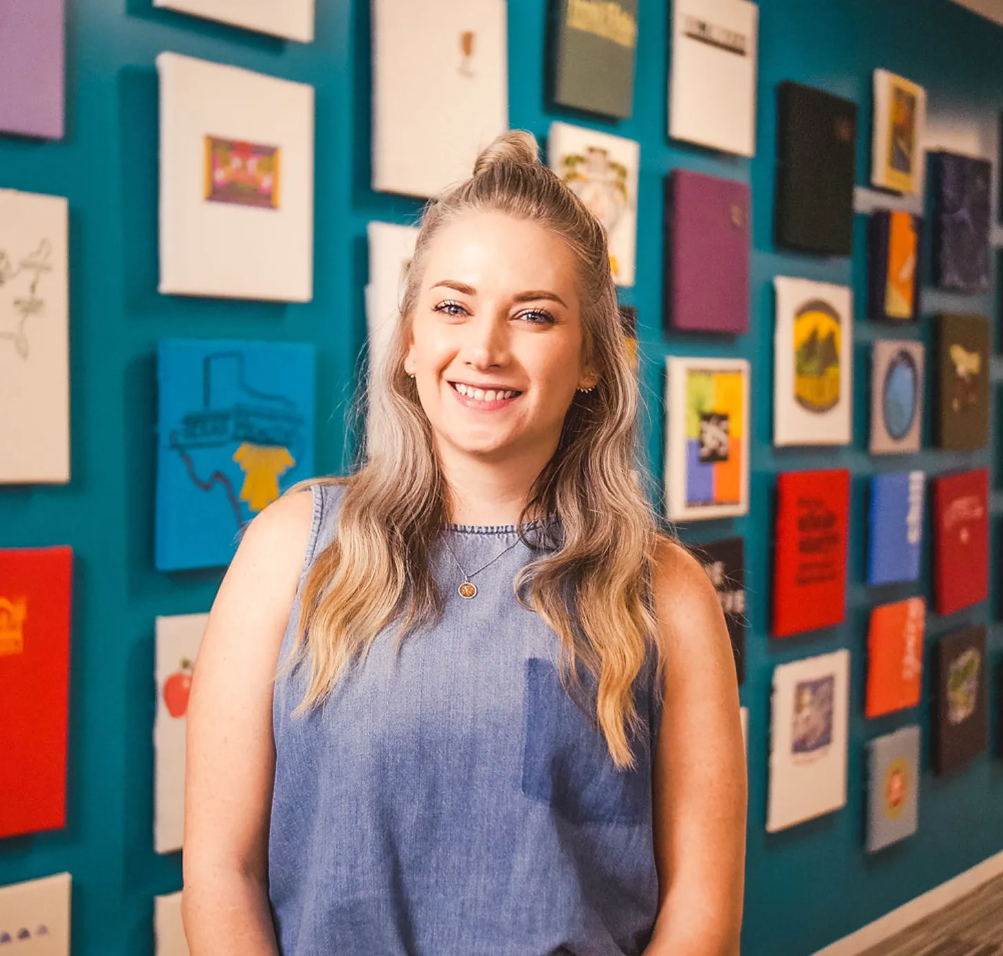 Smiling woman in front of a wall with framed artwork in a store support office.