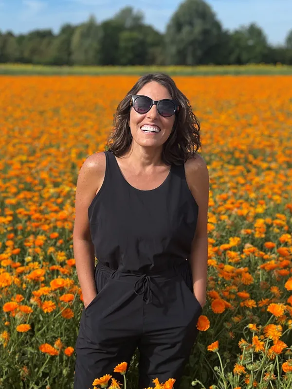 Woman smiling in a field of orange flowers representing exclusive discounts and time off.