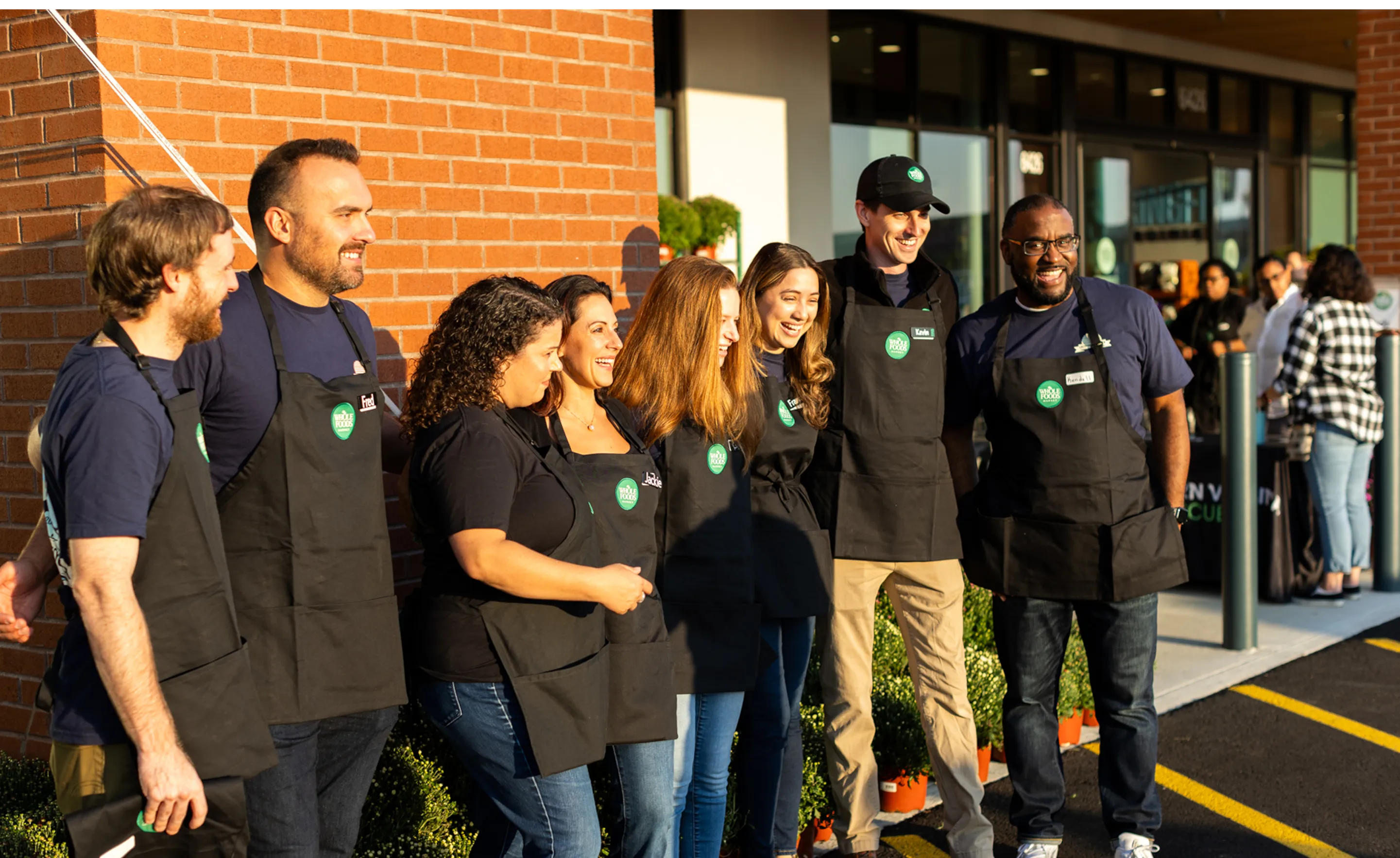 Smiling Whole Foods Market team members stand together outside a store