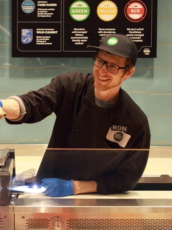 Whole Foods employee Ron smiling while preparing food, demonstrating customer satisfaction.
