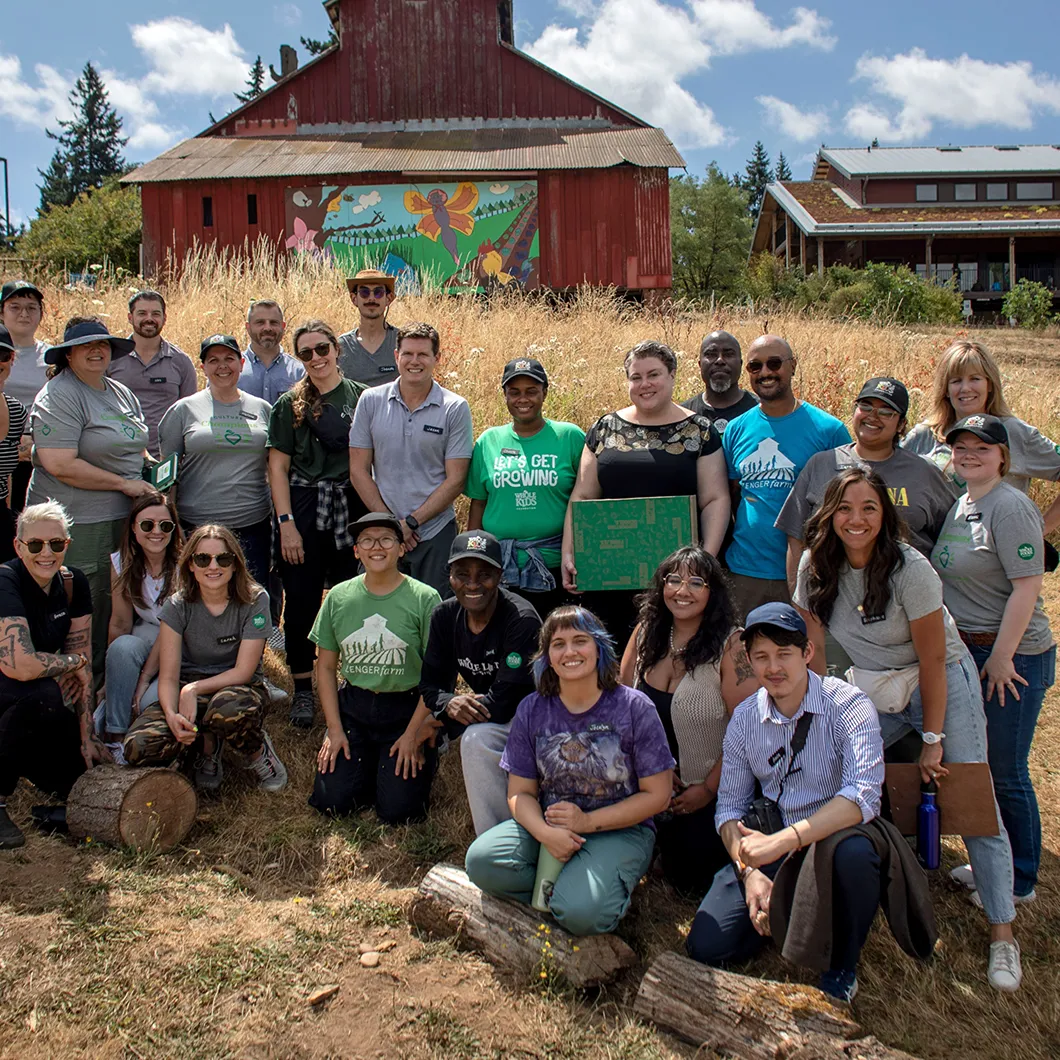 Group of Whole Foods Market employees posing outdoors in front of a red barn with a mural, promoting company culture.