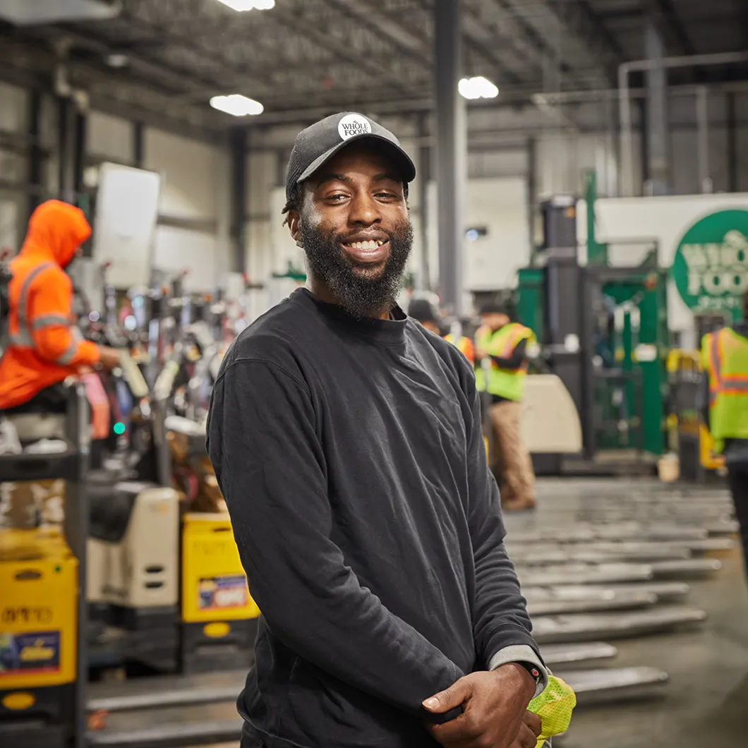 Smiling Whole Foods Market warehouse worker wearing a hat, promoting non-retail careers.