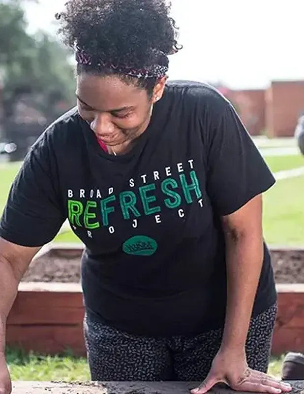 Woman tending to a garden as part of the Broad Street Refresh Project community initiative.