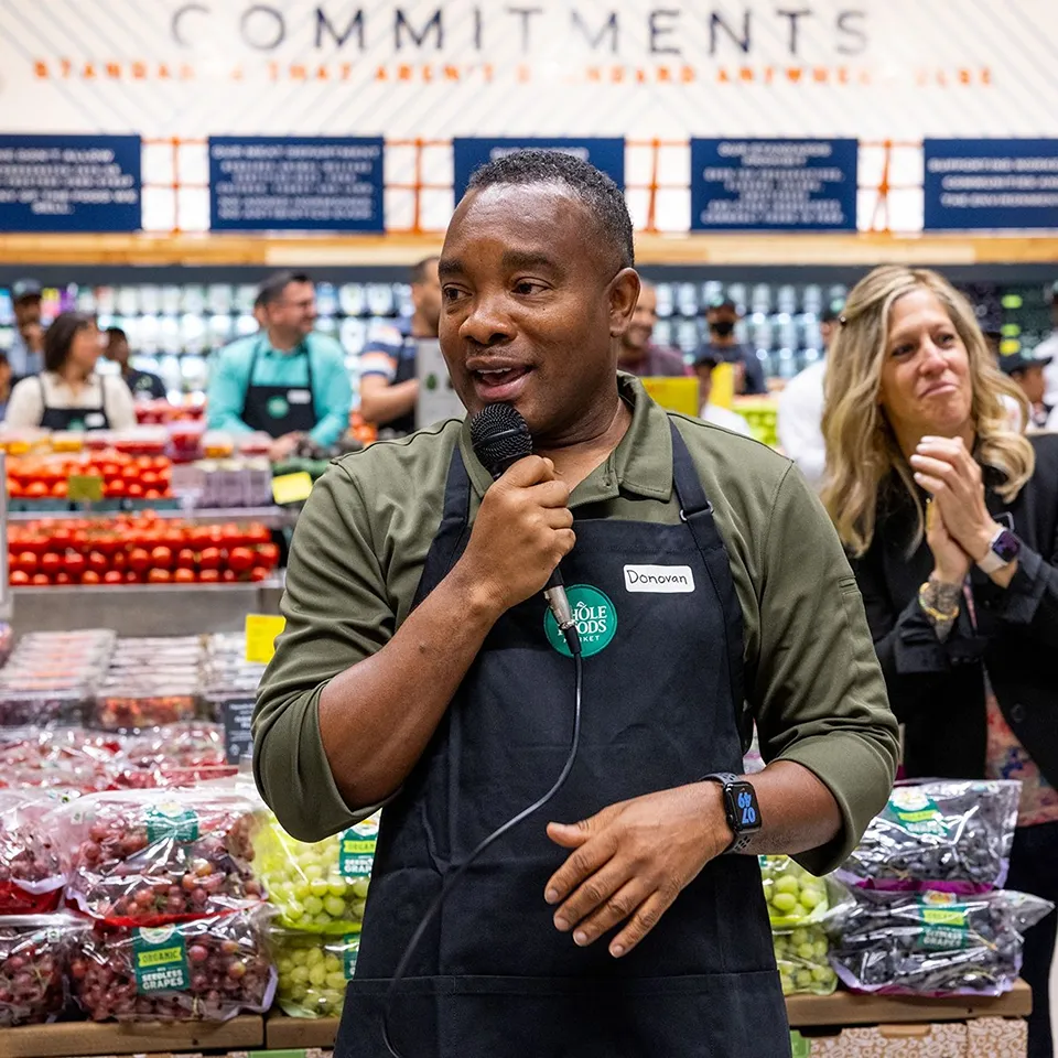 Donovan, Store Team Leader, speaking into a microphone at Whole Foods Market.