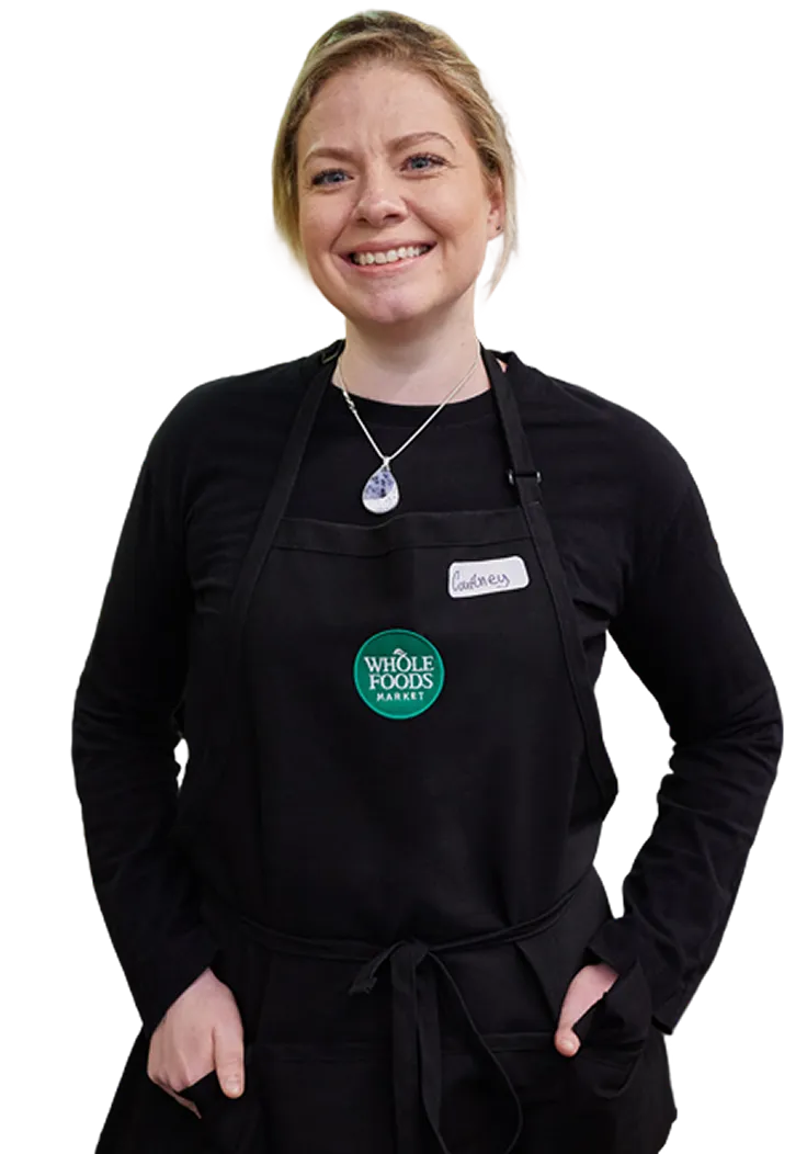 Smiling Whole Foods Market employee wearing a black apron
