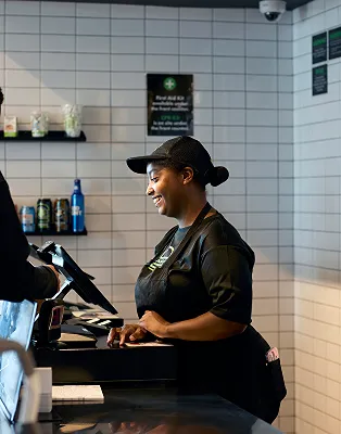 A smiling Shake Shack employee using a point of sale system