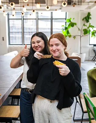 Two Shake Shack employees smiling and holding food