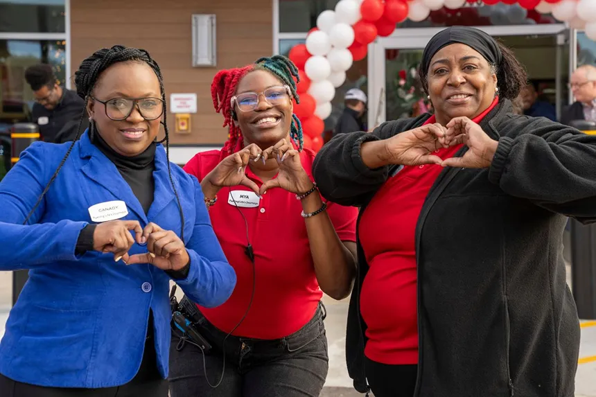 Three cheerful Pilot Company employees are posing and making heart shapes with their hands.