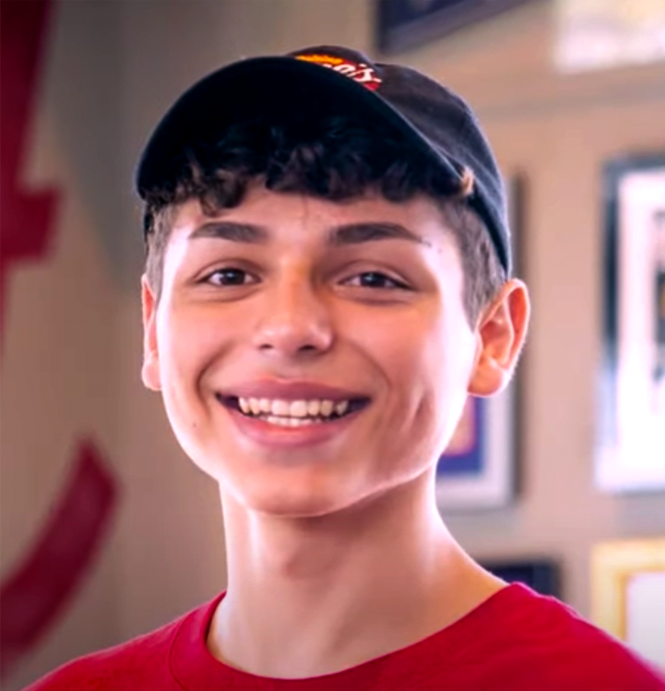 a young boy wearing a red shirt and a baseball cap
