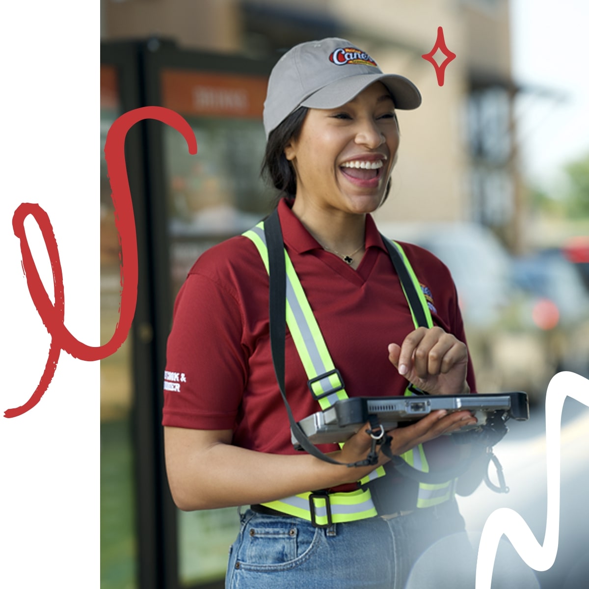 A female employee at Raising Cane's holding a tablet and laughing